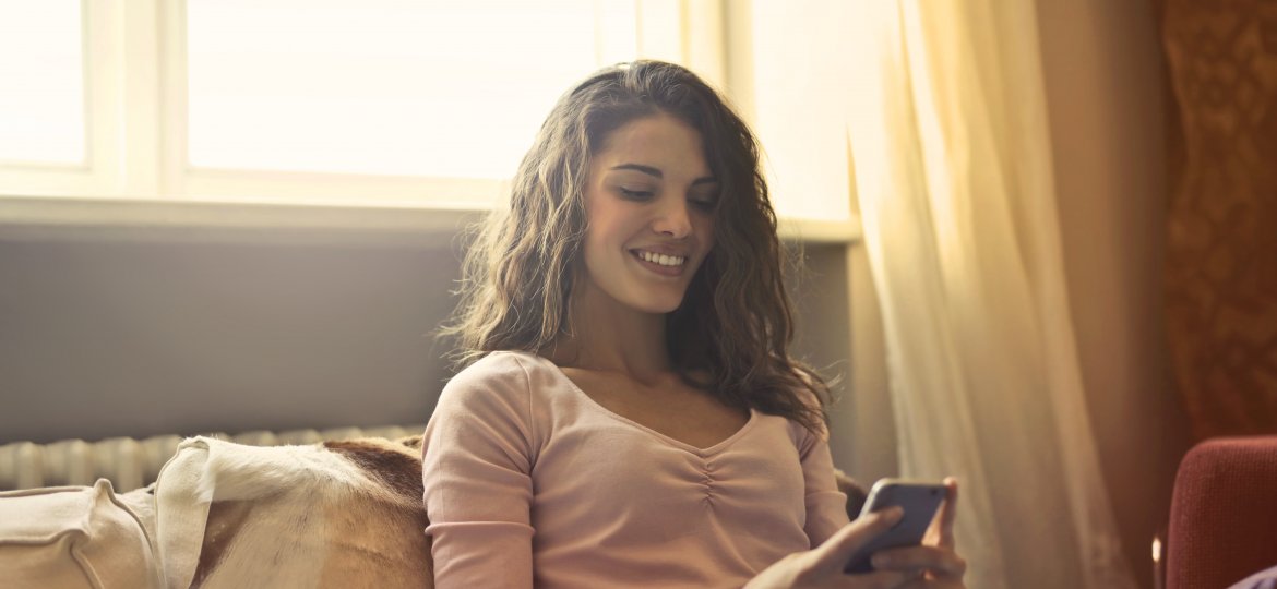 woman-reclining-on-bed-using-a-smartphone-3772514